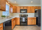 Thumbnail 54 of 58 - A kitchen with wooden cabinets and black appliances.