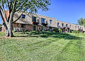 Thumbnail 3 of 10 - A tree stands in front of a brick building with a lawn in the foreground.