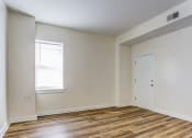 Thumbnail 10 of 18 - a bedroom with white walls and wood flooring and a door