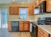 Thumbnail 55 of 58 - A kitchen with wooden cabinets and a black stove top oven.