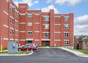 Thumbnail 2 of 20 - Mount Joy Senior Housing | a large red building with a parking lot in front of it