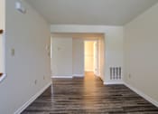 Thumbnail 47 of 58 - A long, empty hallway with wood flooring and white walls.