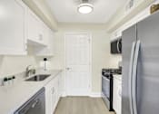 Thumbnail 1 of 39 - A kitchen with white cabinets and a black fridge.