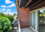 Thumbnail 18 of 39 - A red brick wall with a glass door and a white railing.