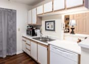 Thumbnail 9 of 20 - A kitchen with white cabinets and a grey curtain.