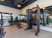 Thumbnail 19 of 67 - A gym with a variety of equipment including a squat rack, bench press, and a mirror.