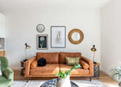 Thumbnail 5 of 67 - A living room with a brown couch, green chair, and a plant.