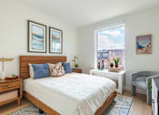 Thumbnail 6 of 67 - A bedroom with a large bed, a nightstand, and a chair.