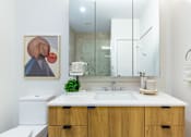 Thumbnail 55 of 67 - A bathroom with a white counter top and a brown cabinet.