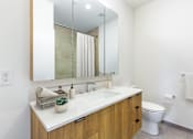 Thumbnail 67 of 67 - A bathroom with a white counter top and a white toilet.