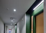 Thumbnail 24 of 67 - a long corridor with wooden doors and white walls