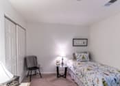 Thumbnail 7 of 20 - A bedroom with a bed, chair, and two lamps.