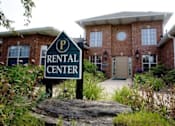 Thumbnail 1 of 20 - A rental center sign is in front of a brick building.