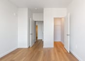 Thumbnail 30 of 67 - A long hallway with white walls and wood floors.