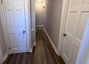 Thumbnail 4 of 23 - A hallway with two doors and wood floors.