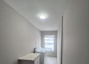 Thumbnail 6 of 23 - A long hallway with a desk and a window.