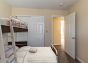 Thumbnail 2 of 10 - A bedroom with a bunk bed and a carpeted floor.