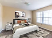 Thumbnail 4 of 9 - A bedroom with a bed, nightstand, and a painting on the wall.
