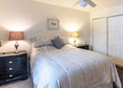 Thumbnail 5 of 20 - A bedroom with a bed, nightstand, and a ceiling fan.