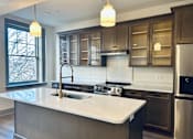 Thumbnail 12 of 15 - a kitchen with a large island and stainless steel appliances