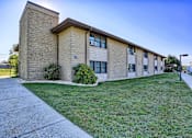 Thumbnail 1 of 2 - a brick building with green grass and a sidewalk