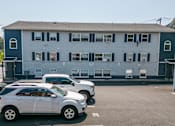 Thumbnail 5 of 5 - a blue building with cars parked in front of it