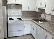 Thumbnail 3 of 5 - an empty kitchen with white cabinets and appliances and a sink