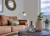 Thumbnail 58 of 67 - A brown couch with a green pillow and a lamp on a table.