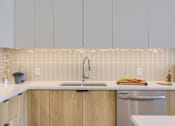 Thumbnail 13 of 67 - A kitchen with a white countertop and wooden cabinets.