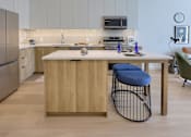 Thumbnail 3 of 67 - A kitchen with a white counter and a blue stool.