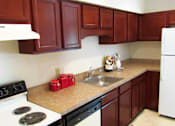Thumbnail 4 of 10 - A kitchen with a white stove and brown cabinets.