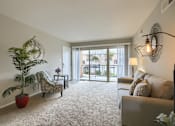 Thumbnail 6 of 16 - Mechanicsburg Apartments | Delbrook Manor Apartments | a living room with a couch chair and a potted plant in front of a sliding glass