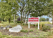 Thumbnail 1 of 16 - Mechanicsburg Apartments | Delbrook Manor Apartments | a sign in front of a grassy area with trees in the background
