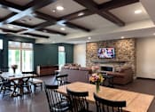 Thumbnail 6 of 19 - A living room with a stone fireplace and a television mounted above it.
