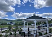 Thumbnail 9 of 19 - A gazebo is surrounded by a white fence and has a black roof.