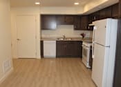Thumbnail 12 of 19 - A kitchen with white appliances and brown cabinets.