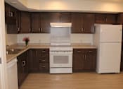 Thumbnail 11 of 19 - A kitchen with white appliances and brown cabinets.
