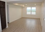Thumbnail 13 of 19 - A room with wooden flooring and a window overlooking a field.