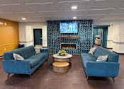 Thumbnail 4 of 19 - A living room with two blue couches and a fireplace.