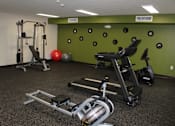 Thumbnail 7 of 19 - A gym with a green wall and a variety of exercise equipment.