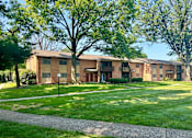Thumbnail 1 of 48 - Apartment complex with green grass and trees.