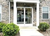 Thumbnail 15 of 37 - The front of a building with a stone facade and a glass door.