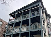 Thumbnail 21 of 23 - A green building with a balcony and stairs leading to the second floor.