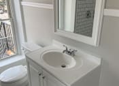Thumbnail 5 of 13 - A white bathroom with a toilet, sink, and mirror.