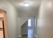 Thumbnail 8 of 13 - A long hallway with wood floors and white walls.
