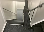 Thumbnail 13 of 13 - A stairway with a black handrail and a black step.