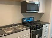 Thumbnail 1 of 13 - A modern kitchen with a black stove top oven and a black microwave above it.