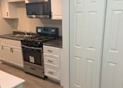 Thumbnail 2 of 13 - A kitchen with white cabinets and a black stove top oven.