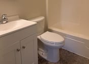 Thumbnail 5 of 7 - A white toilet sits next to a sink in a bathroom.