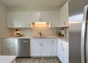 Thumbnail 4 of 48 - A kitchen with white cabinets and a stainless steel refrigerator.